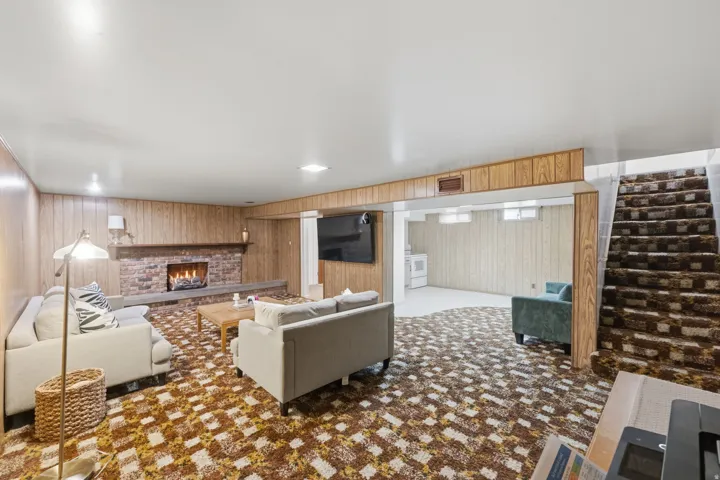 Spacious room featuring wood paneling, a brick fireplace, and wall-to-wall carpeting