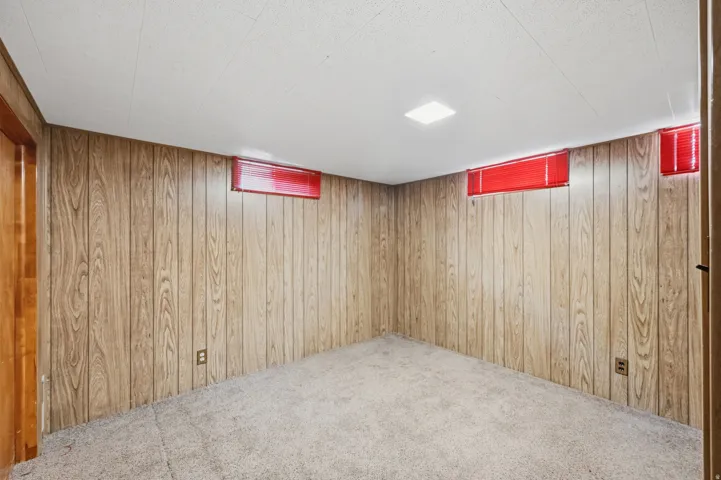 Wood-look paneling accents a carpeted room with a drop ceiling