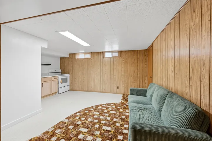 Wood-paneled wall, built-in cabinetry, light-colored flooring, window openings, and an overhead light fixture
