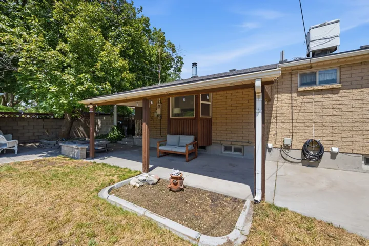 Covered patio area with concrete flooring, brick exterior, and a built-in planter