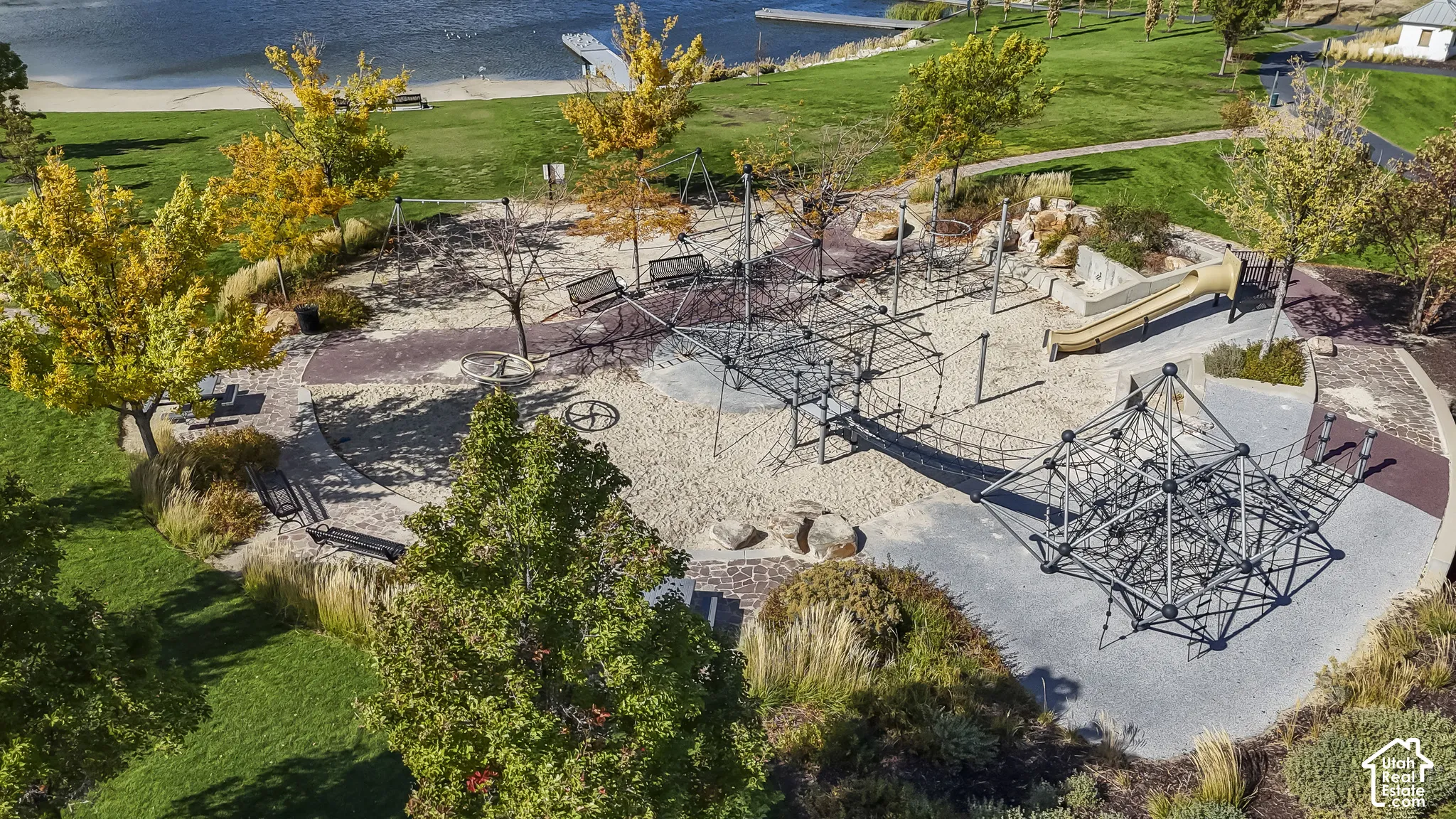 Recreational area featuring multiple play structures, sand surfacing, a slide, and swings