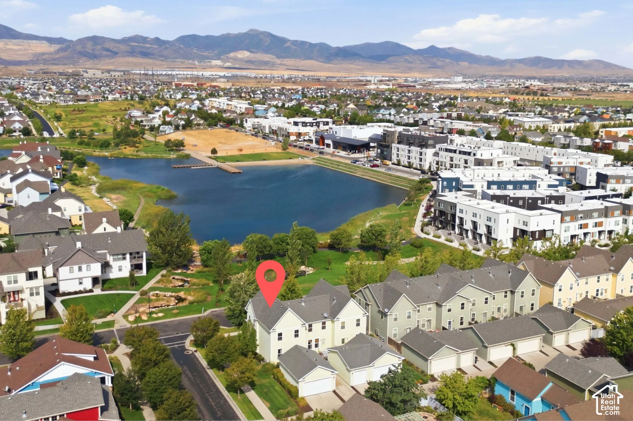 Aerial perspective showcasing the residential neighborhood with a prominent lake, surrounding green spaces, and mountain backdrop