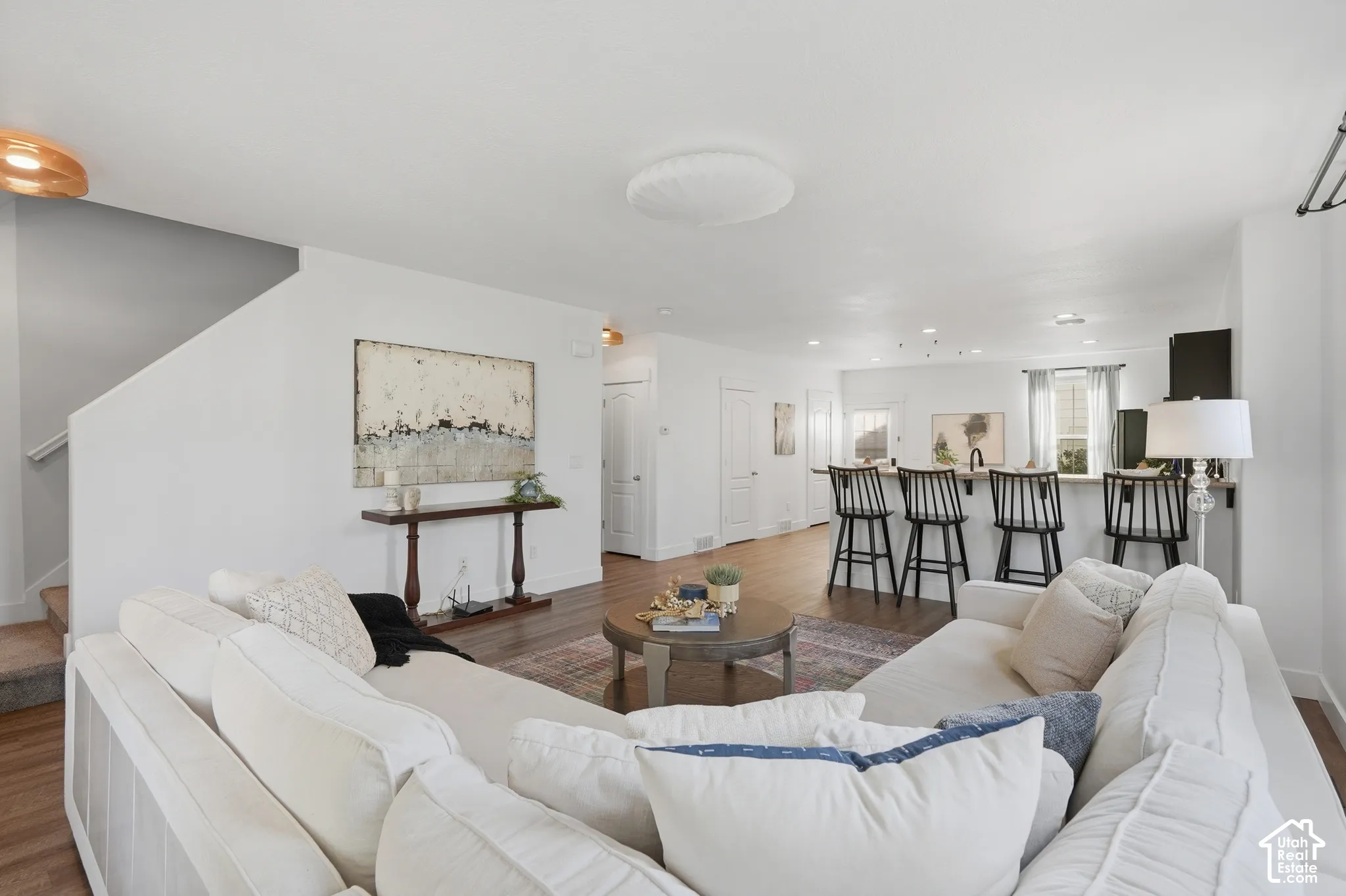 Open-concept living space with wood-finish flooring, recessed lighting, and a breakfast bar