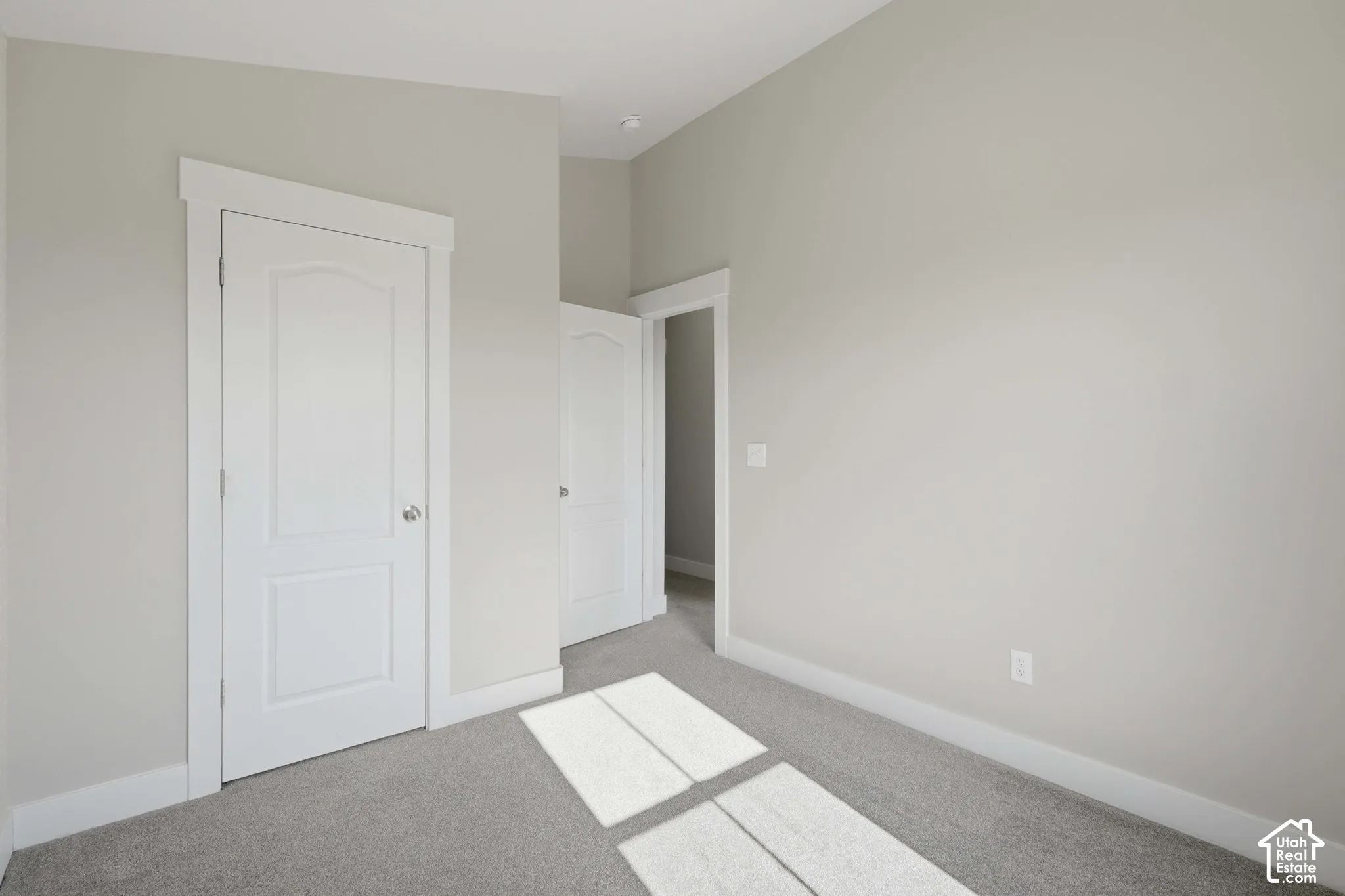 Neutral wall paint, white trim, two panel interior doors, and carpeted flooring