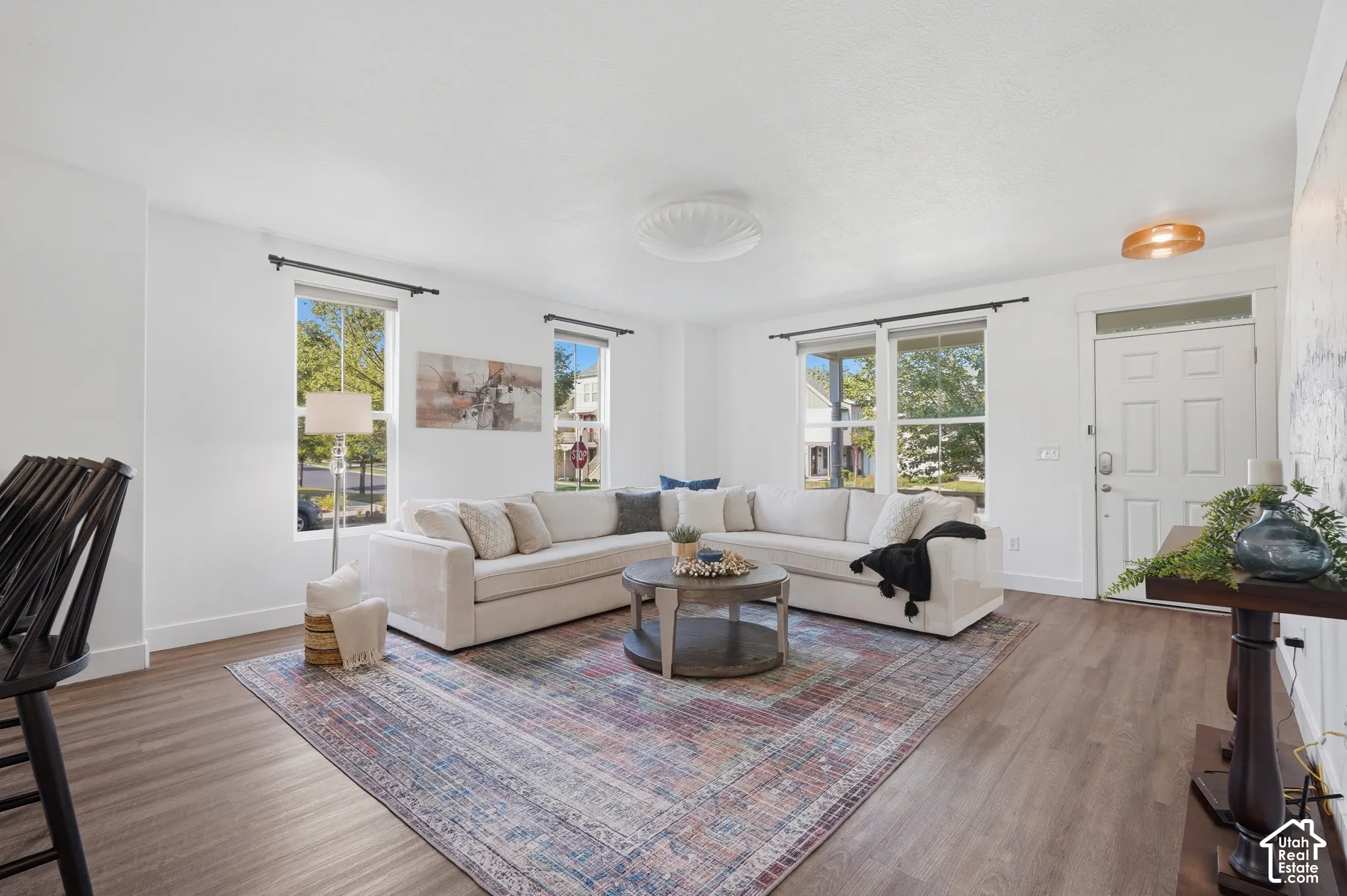 Spacious living area featuring wood-finish flooring, multiple windows, recessed lighting, and a paneled entry door with transom window