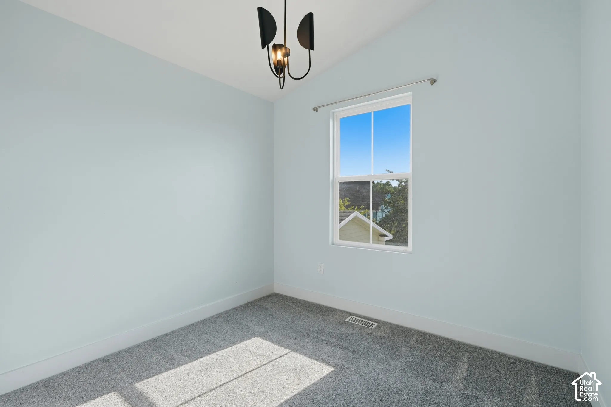 Single window, light blue walls, gray carpet, and a modern ceiling fixture