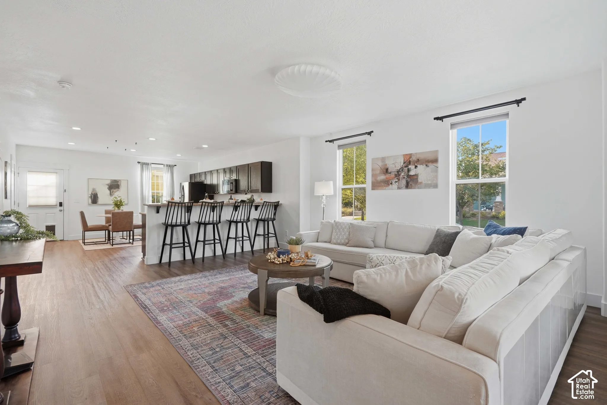 Open-concept living area featuring wood-finish flooring, recessed lighting, and ample natural light from multiple windows