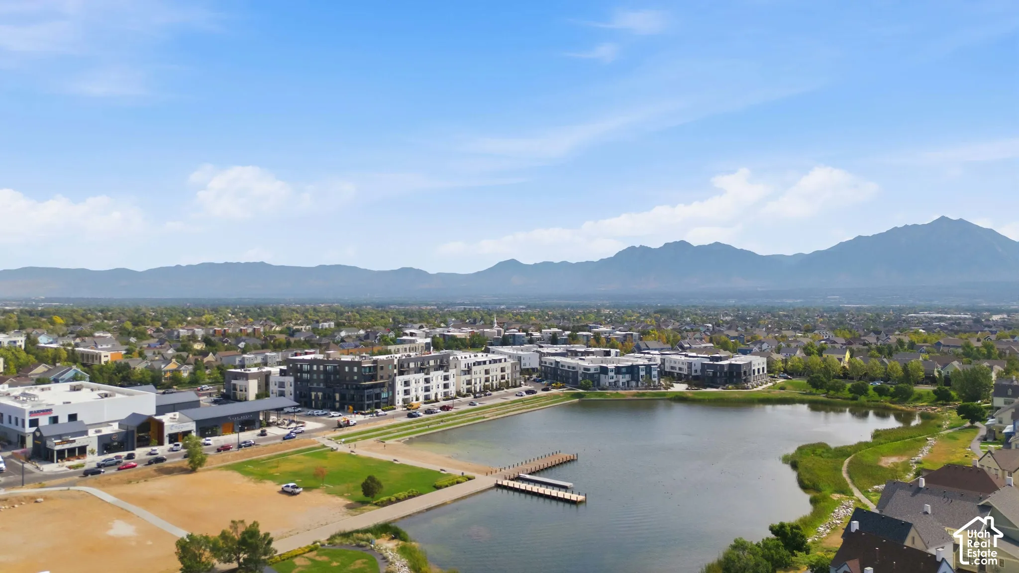 Waterfront property featuring a dock, surrounding residential structures, and distant mountains