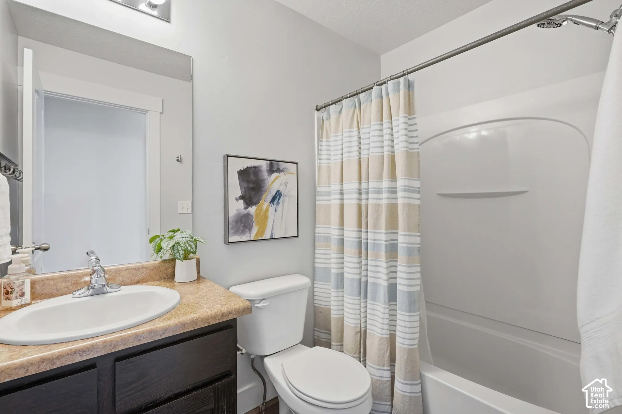 Bathroom featuring a white bathtub, shower combination with a curved shower rod, dark wood-finish vanity with an integrated sink, and an overhead vanity light