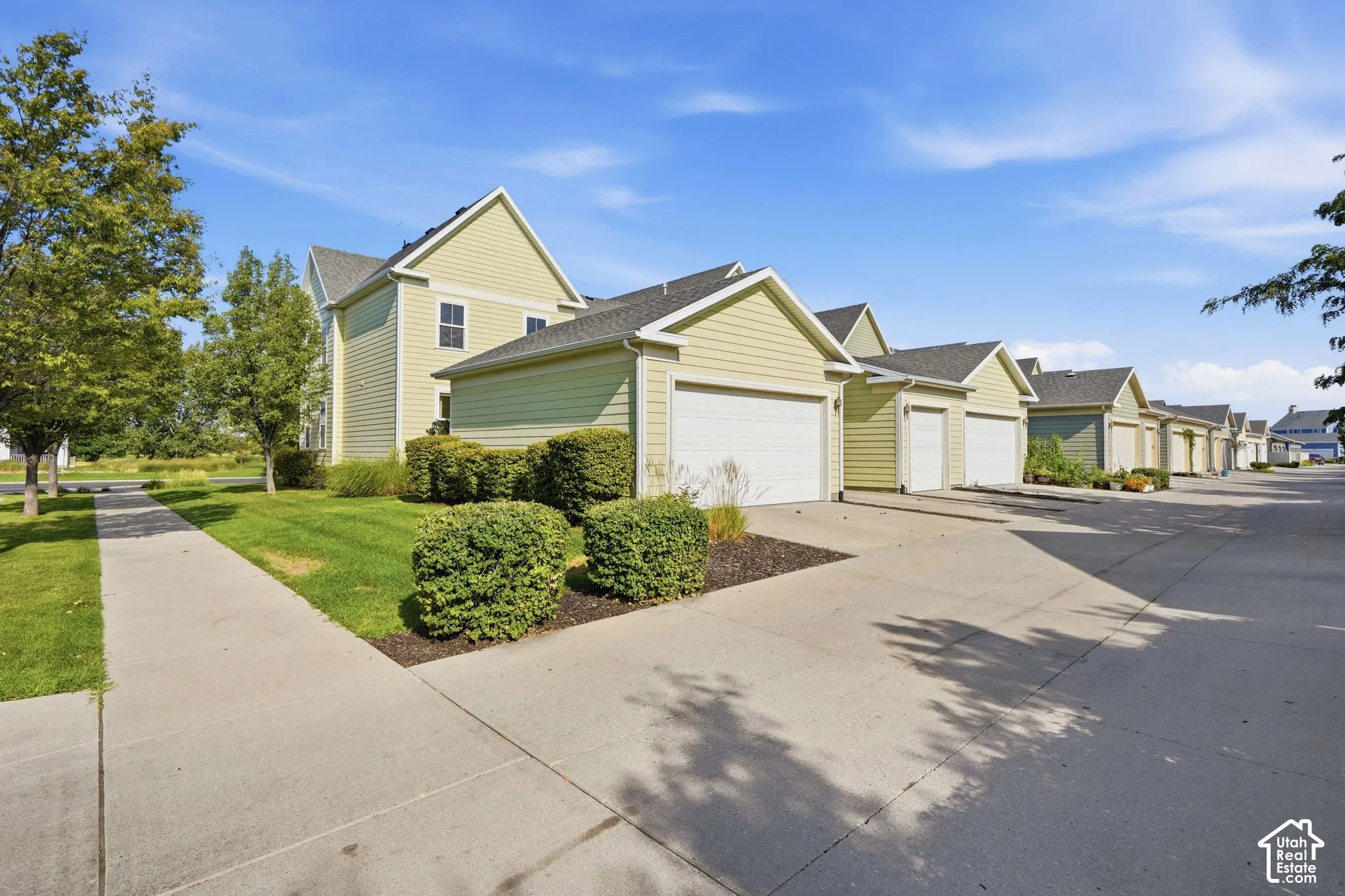 Multiple garages with light green siding and white garage doors