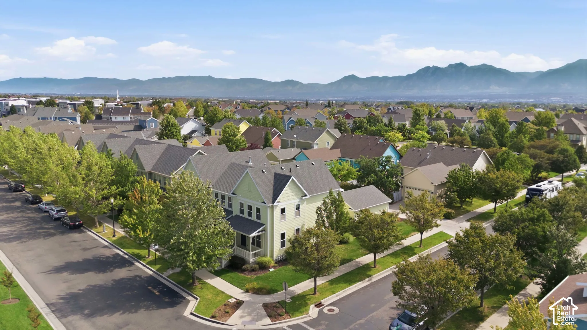 Residential neighborhood featuring a prominent green-hued property with a covered porch and multi-level roofline