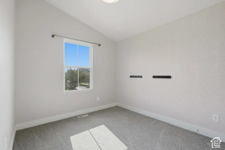 Vaulted ceiling, single window, wall-to-wall carpeting, and neutral wall finishes