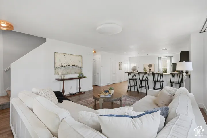 Open-concept living space with wood-finish flooring, recessed lighting, and a breakfast bar