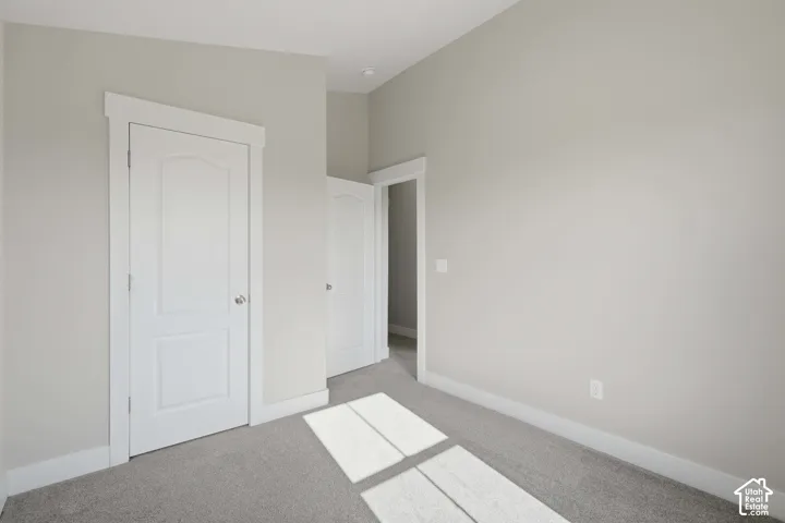 Neutral wall paint, white trim, two panel interior doors, and carpeted flooring