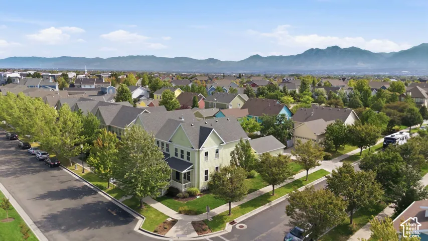 Residential neighborhood featuring a prominent green-hued property with a covered porch and multi-level roofline