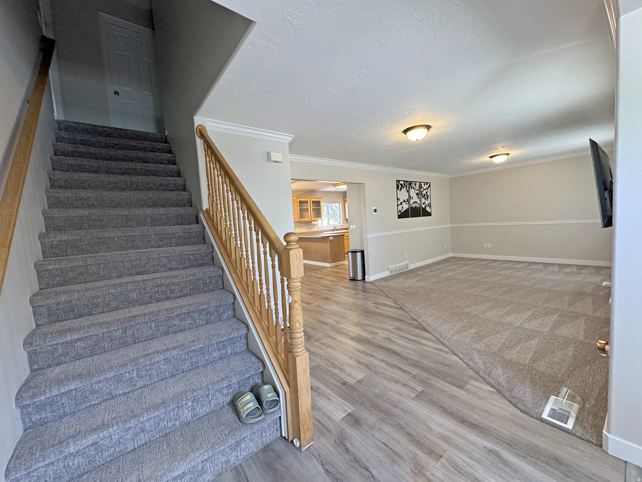 Carpeted staircase with wood banister, wood-finish flooring, recessed lighting, and crown molding