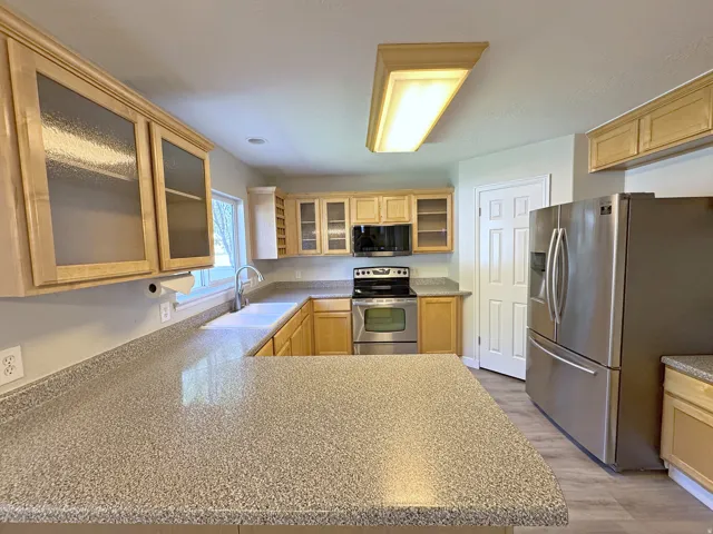 U-shaped kitchen featuring wood-finish cabinetry, speckled countertops, and stainless steel appliances