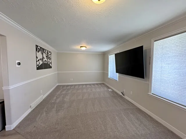 Neutral wall paint, crown molding, chair rail molding, wall-to-wall carpeting, and recessed lighting