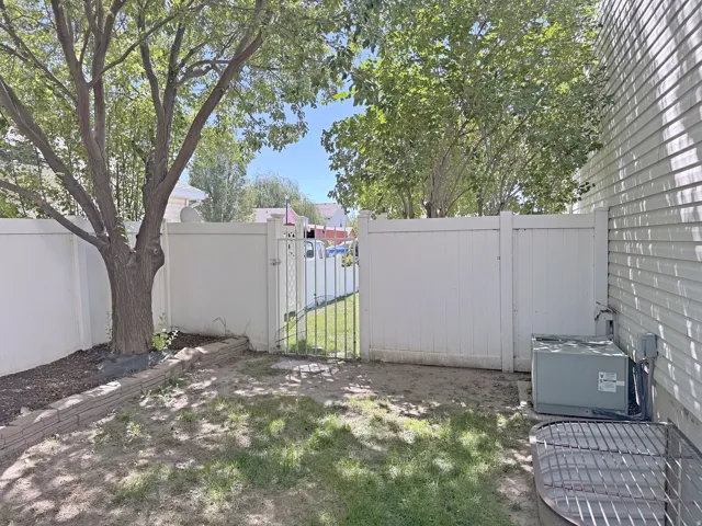 Private fenced yard with a mature tree, stone retaining wall, and side access gate