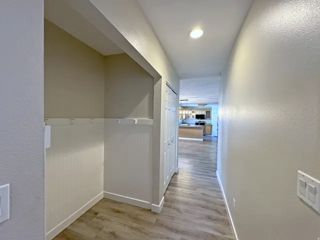Hallway with wood-finish flooring, recessed lighting, and a built-in storage alcove featuring beadboard paneling