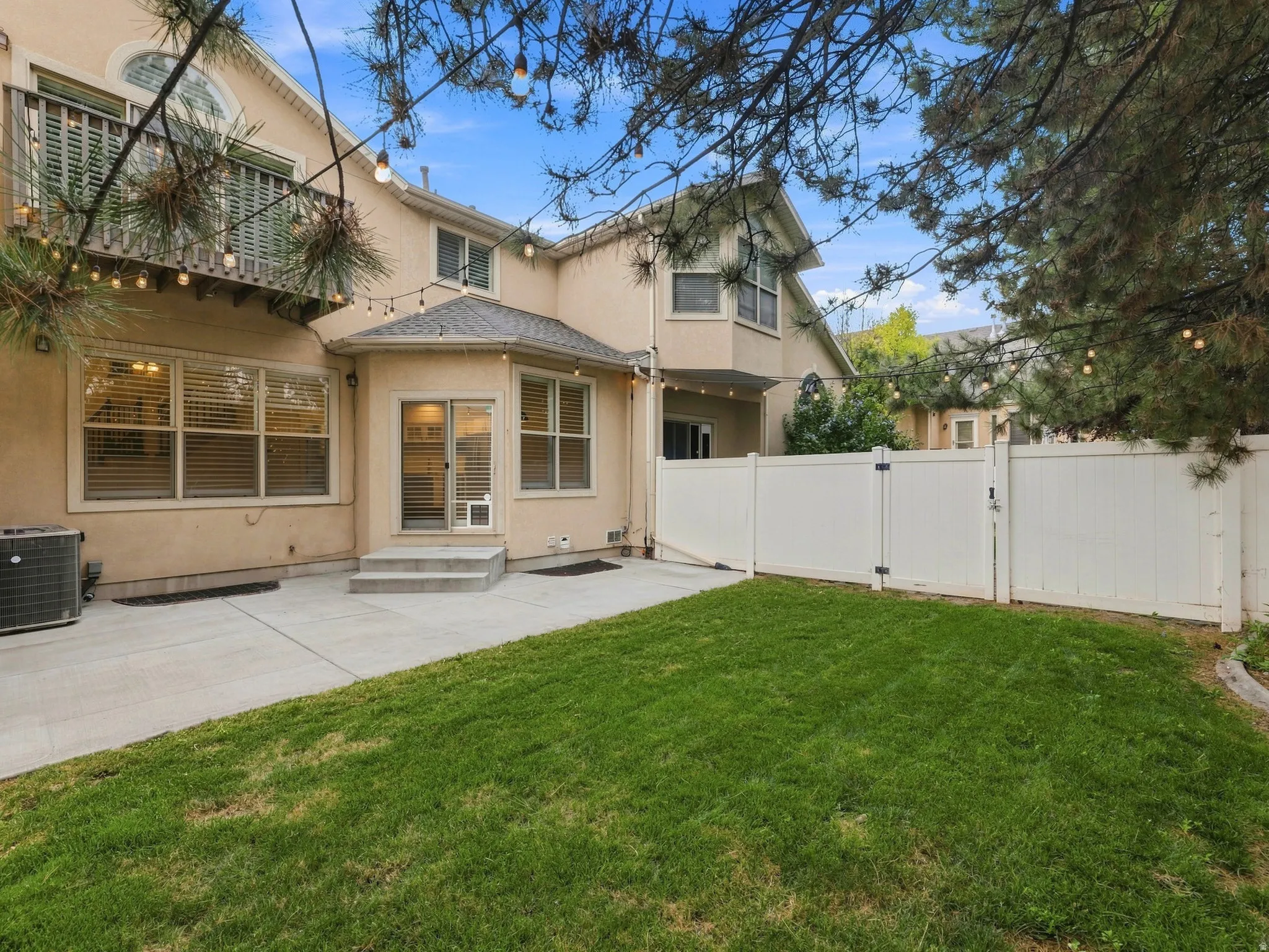 Expansive concrete patio, a manicured lawn, and a white privacy fence