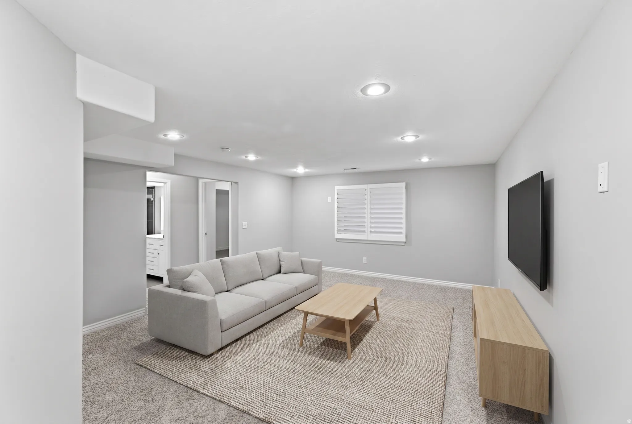 Recessed ceiling lighting, window with white plantation shutters, and a wall-mounted media console