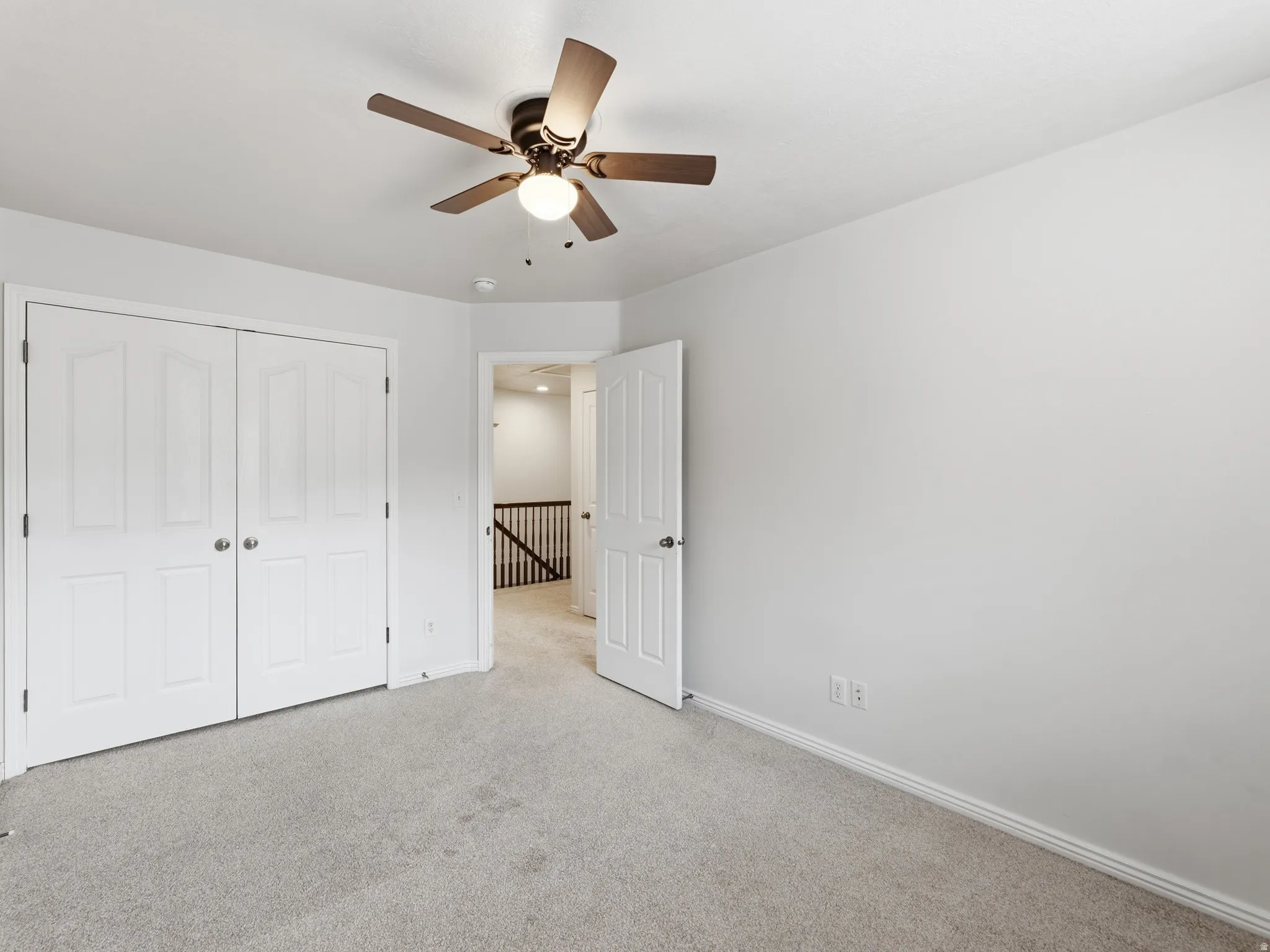Neutral wall color, carpeted flooring, double bi-fold doors, ceiling fan with integrated lighting, and white trim