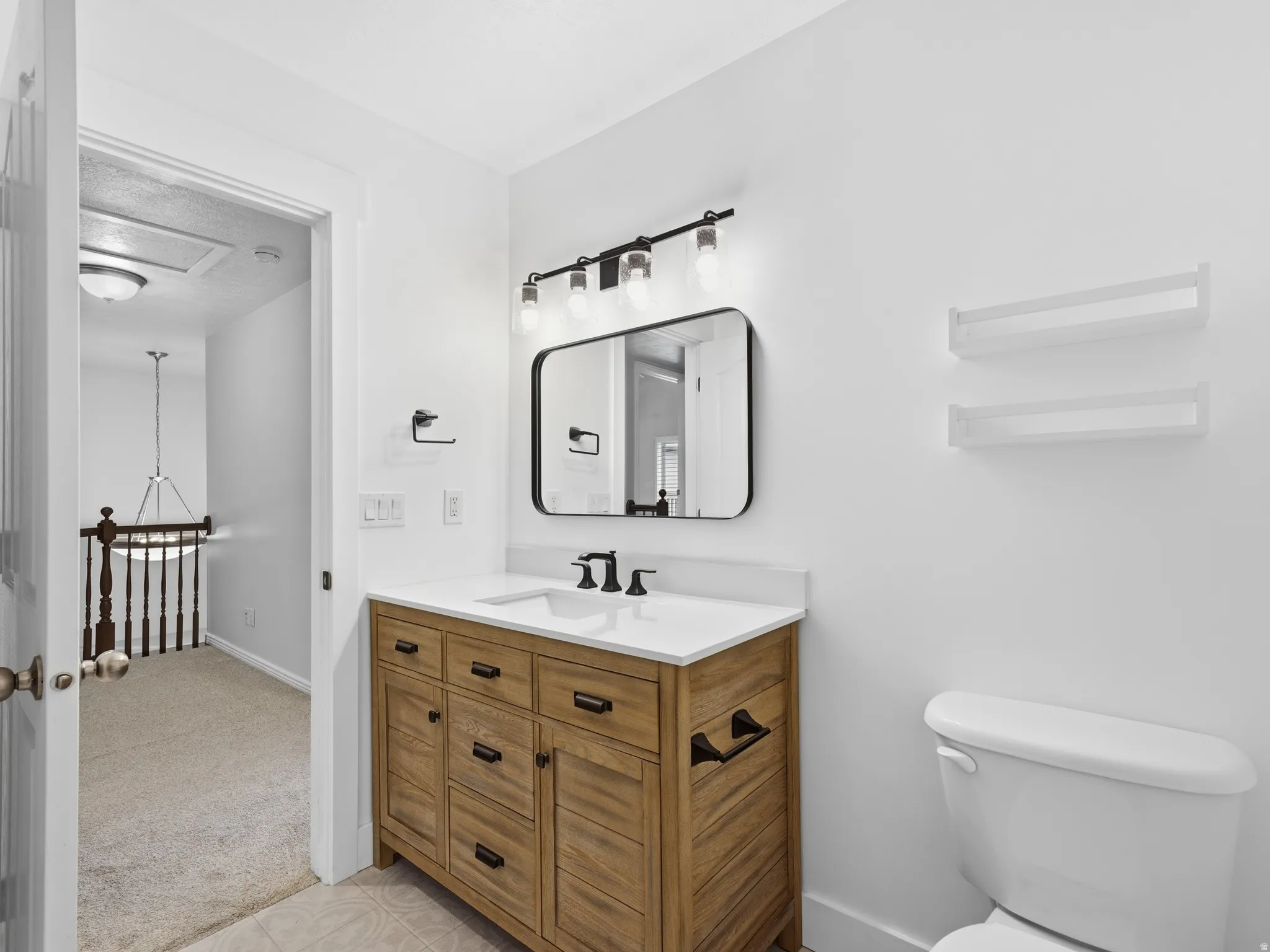 Bathroom featuring a wood-finish vanity with a white countertop, rectangular mirror, and a wall-mounted light fixture