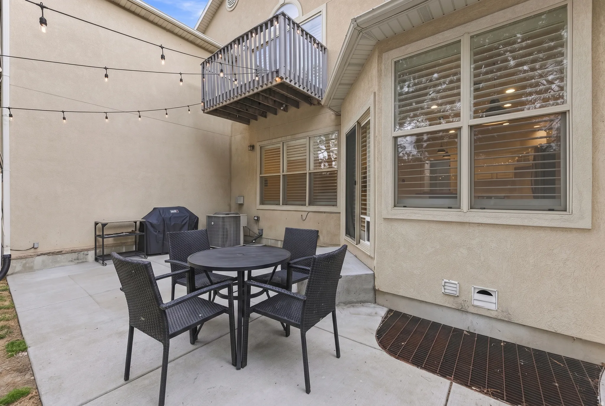 Outdoor patio featuring a concrete surface, string lighting, and an upper-level balcony