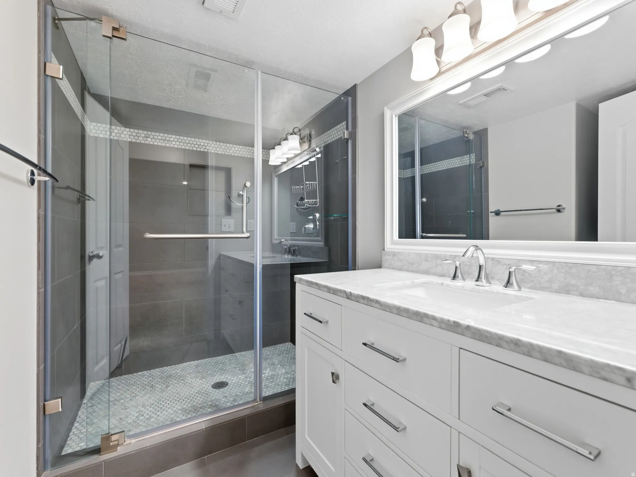 Glass-enclosed shower with a mosaic tile floor and contrasting wall tile
