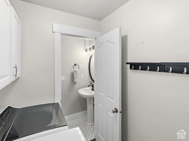 White upper cabinetry with brushed nickel pulls, white interior door, and wall-mounted coat rack