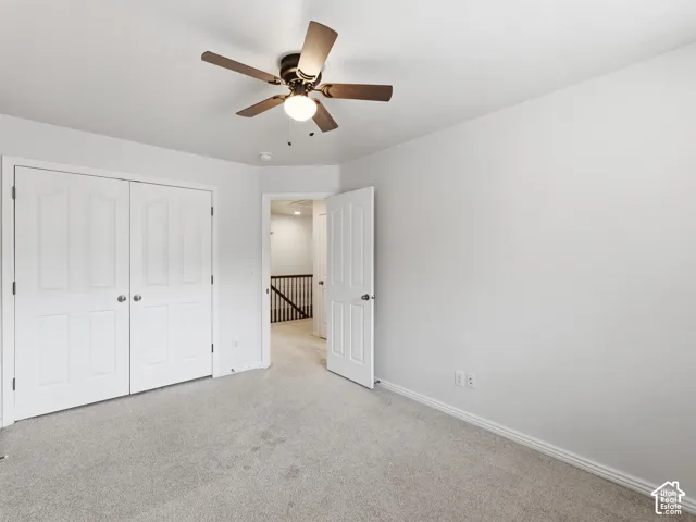 Neutral wall color, carpeted flooring, double bi-fold doors, ceiling fan with integrated lighting, and white trim