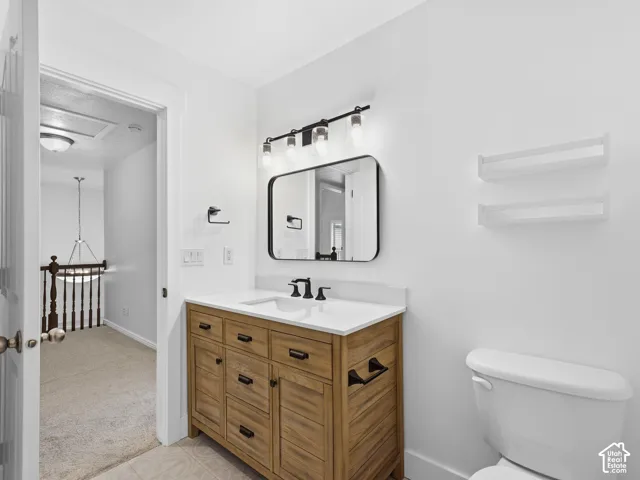 Bathroom featuring a wood-finish vanity with a white countertop, rectangular mirror, and a wall-mounted light fixture