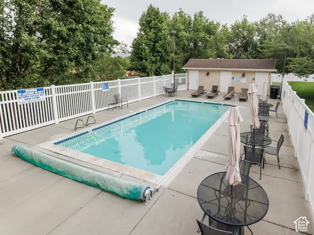 Fenced in-ground swimming pool with surrounding concrete patio