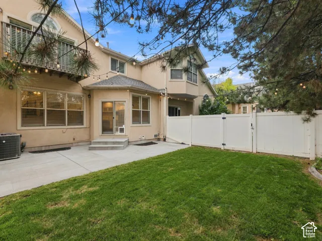Expansive concrete patio, a manicured lawn, and a white privacy fence