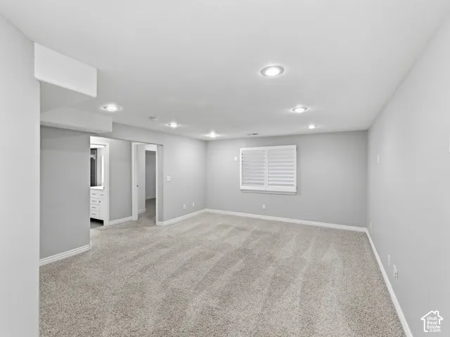 Recessed lighting, light gray wall paint, window with white plantation shutters, gray carpet flooring, and white trim