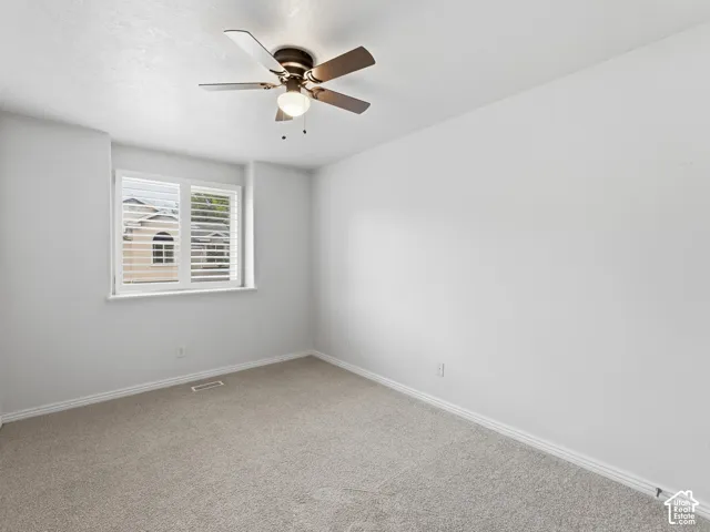 Neutral wall finishes, recessed window with white plantation shutters, textured carpet flooring, and a ceiling fan with integrated lighting
