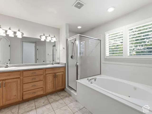 Dual vanity with light wood cabinetry, stone-finish countertop, and undermount sinks