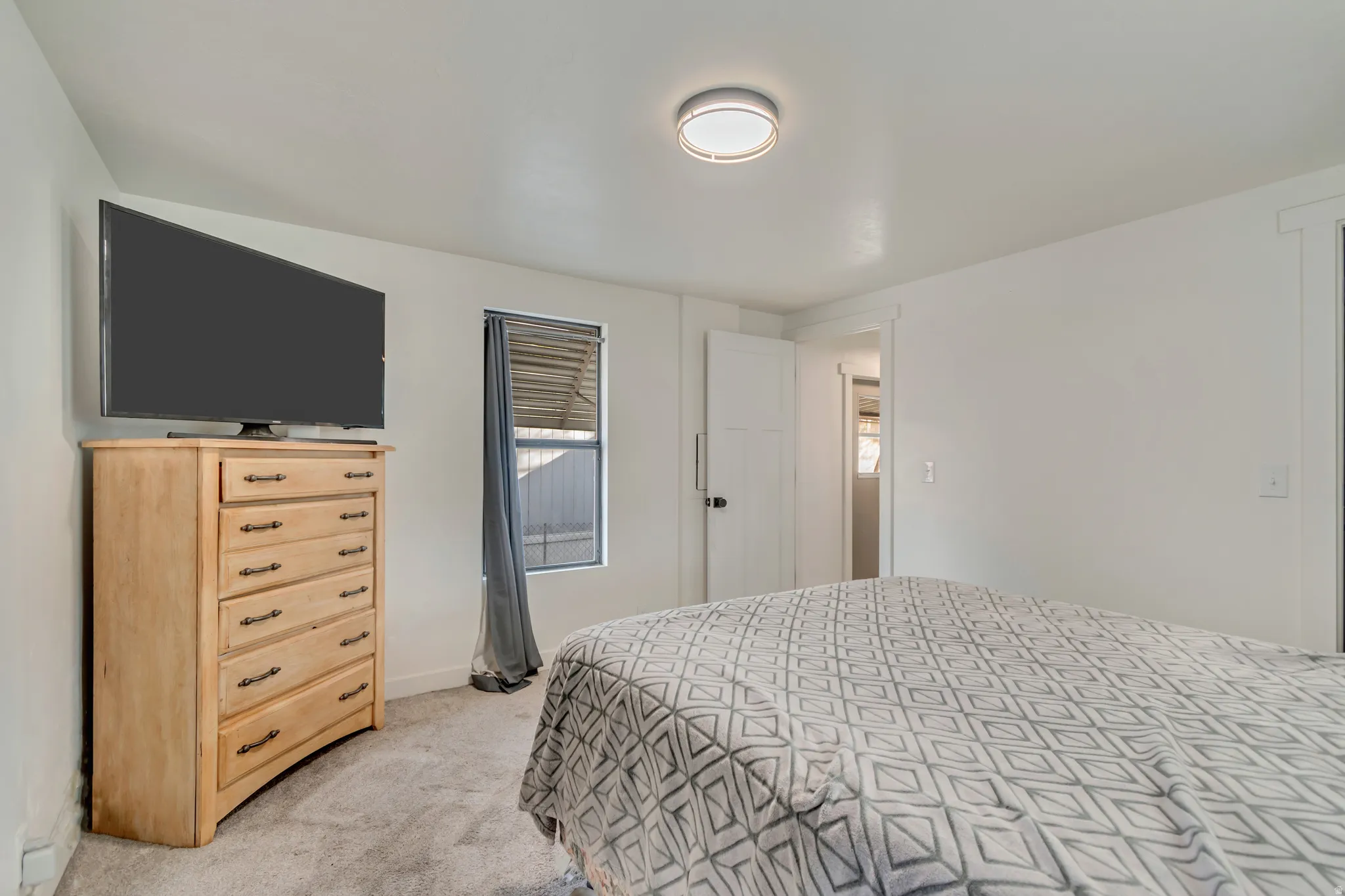 White walls, flush mount ceiling light, light-colored carpeting, and a window with blinds