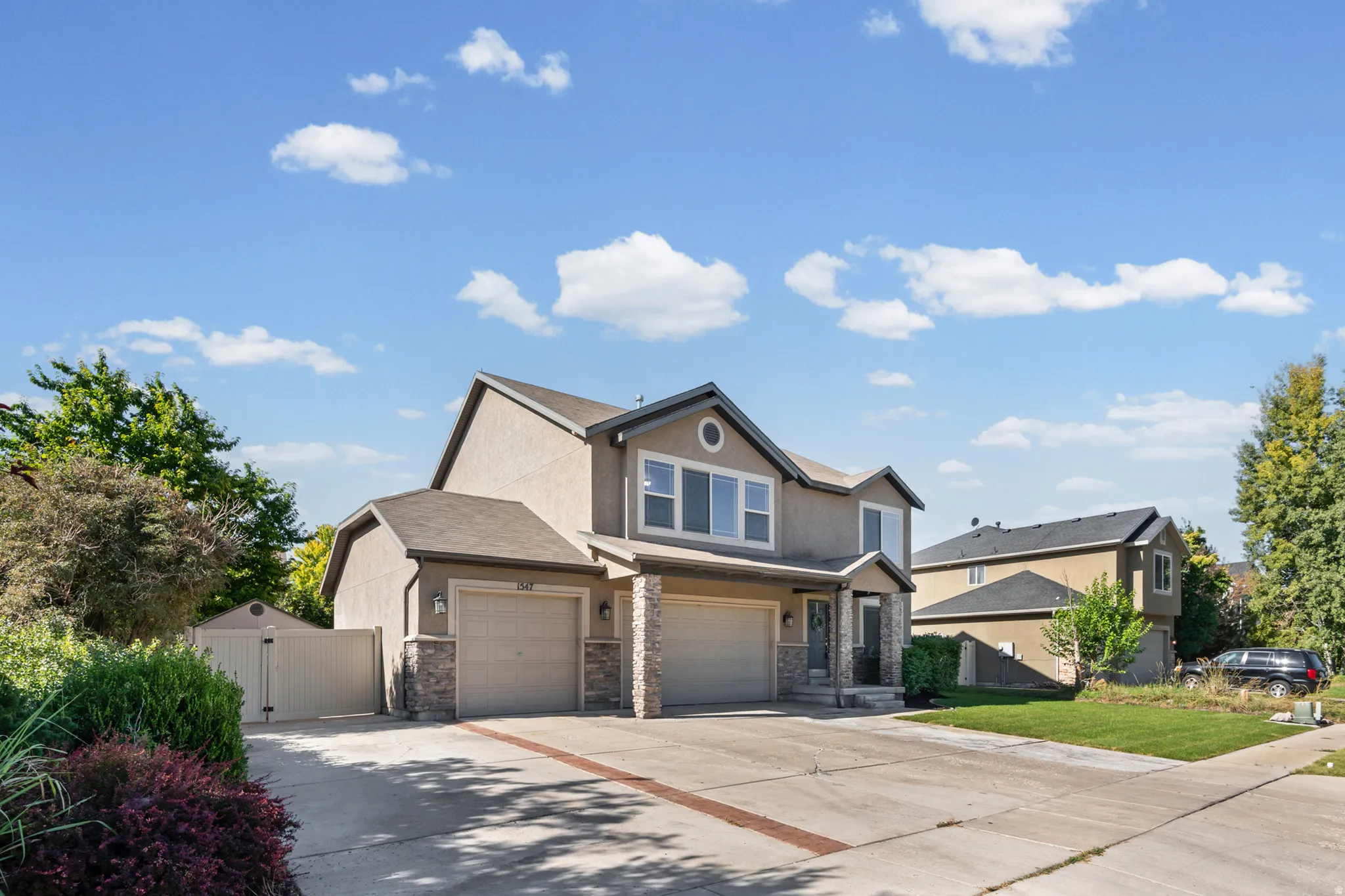 Two-story stucco exterior featuring stone accents, a multi-car garage, and a gated side yard