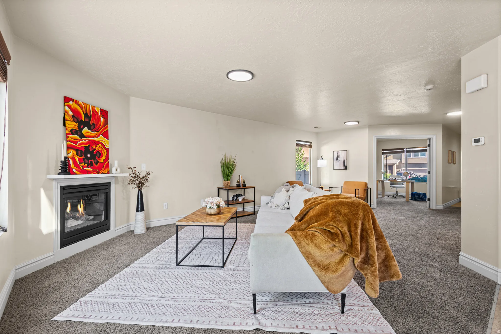Living area featuring a modern fireplace with a white mantel, recessed lighting, and carpet flooring