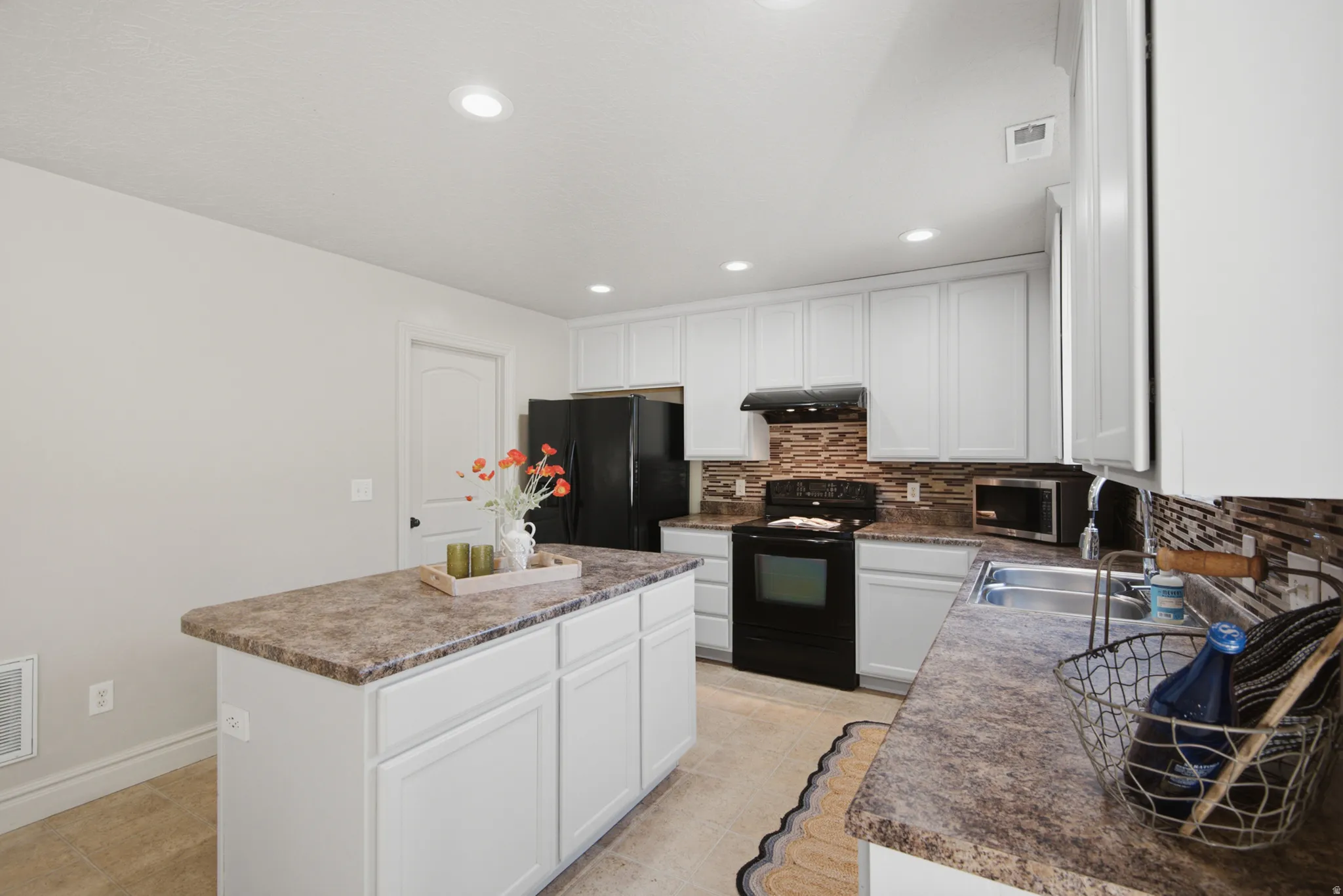 Kitchen featuring white cabinetry, a central island with a countertop, recessed lighting, and a tile backsplash