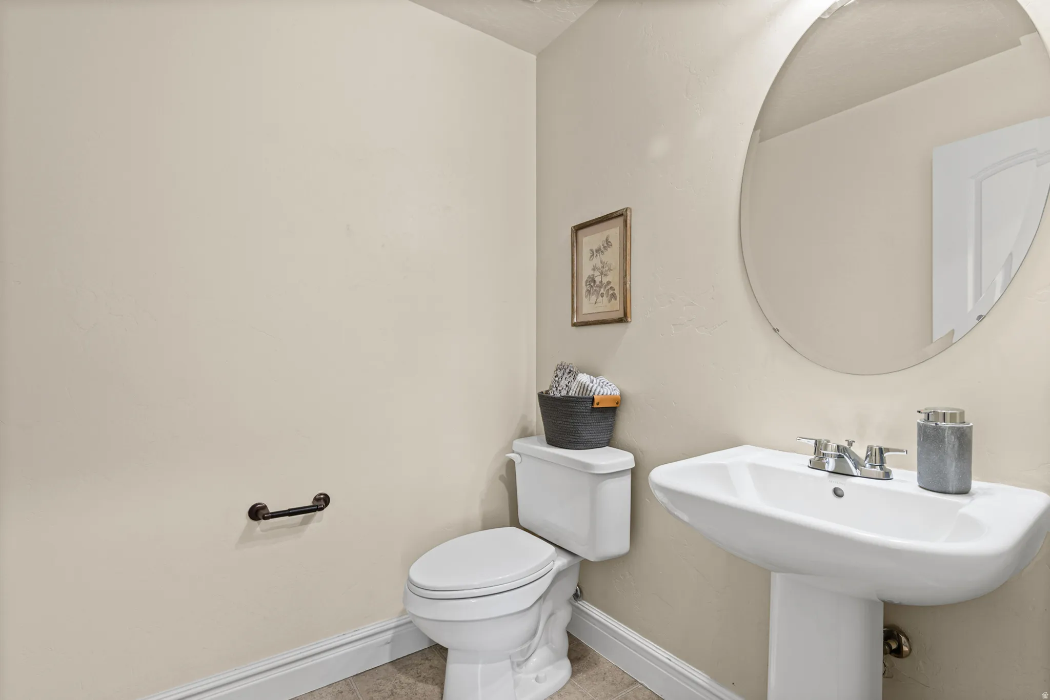 Pedestal sink, wall-mounted mirror, and white toilet