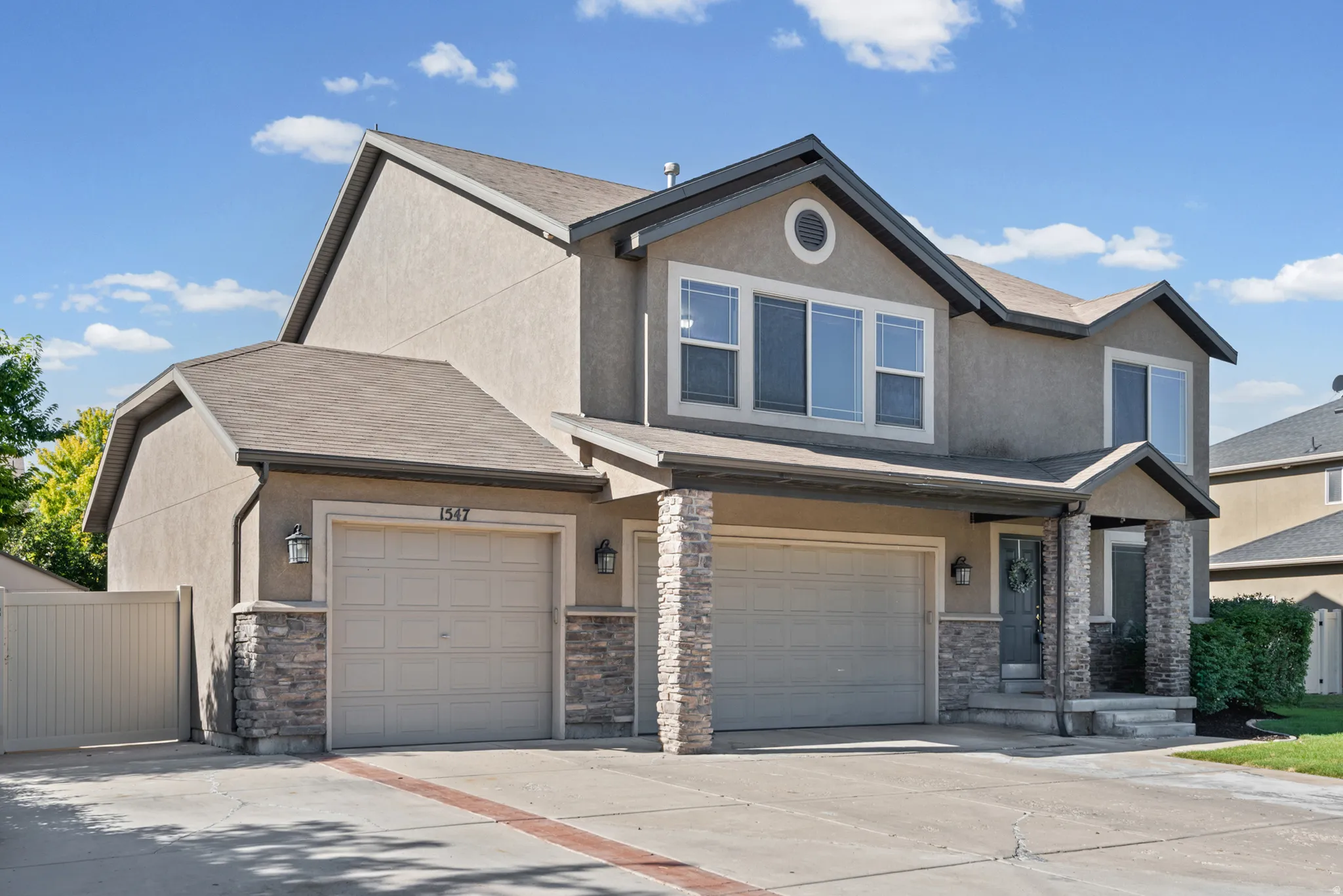 Stucco exterior with stone accents, two-car garage, covered entry, and a paved driveway