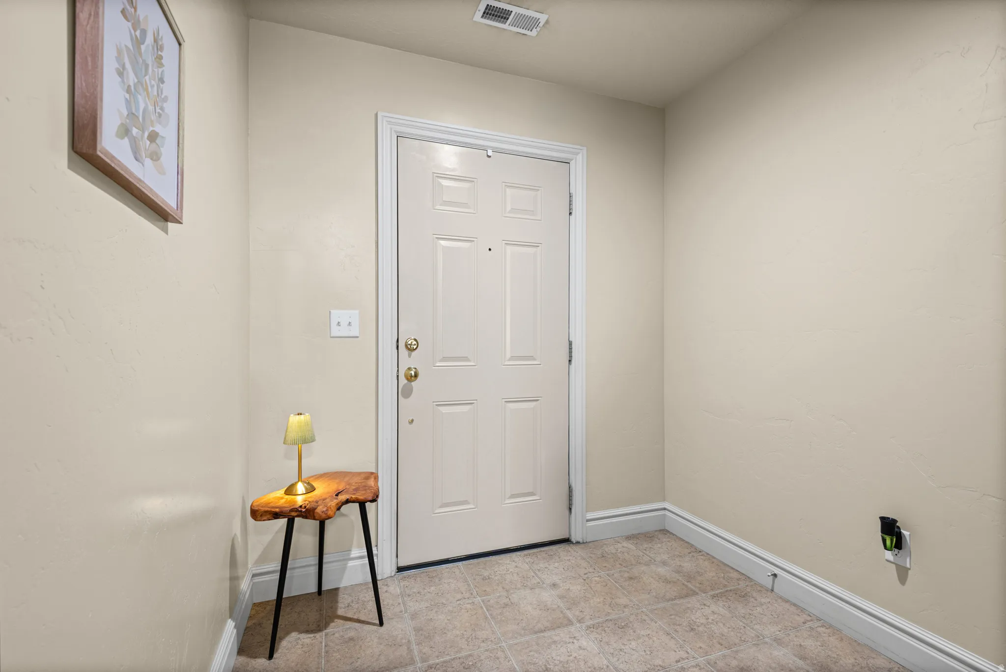 Entryway featuring a paneled door with brass hardware, light-toned wall paint, and tiled flooring