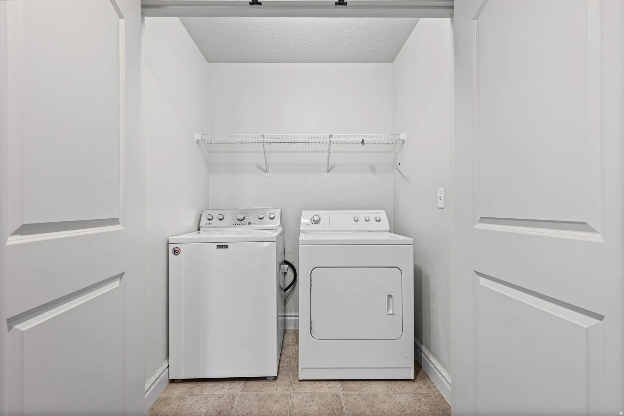 Laundry area featuring a wire shelf, white washer, and white dryer