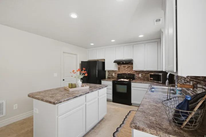 Kitchen featuring white cabinetry, a central island with a countertop, recessed lighting, and a tile backsplash
