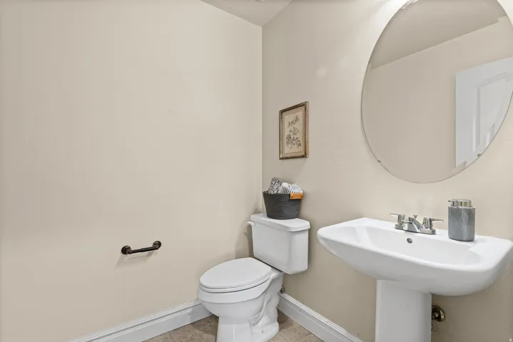 Pedestal sink, wall-mounted mirror, and white toilet