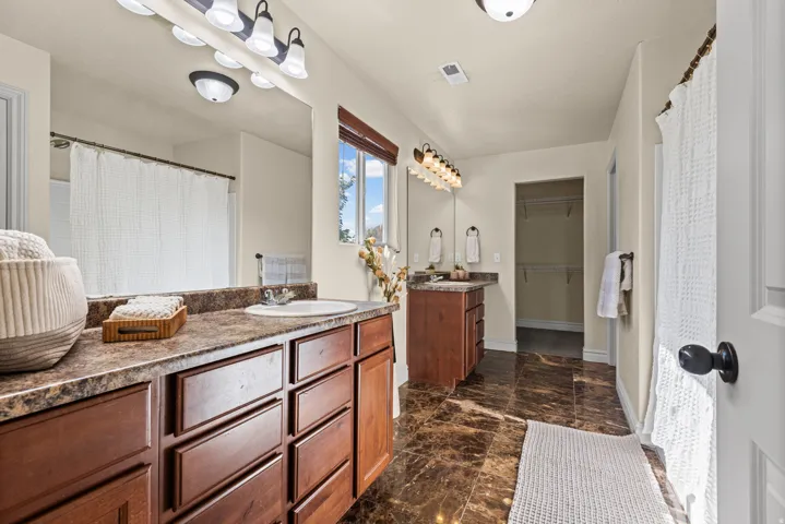 Dual vanity with integrated sinks, rich wood cabinetry, and a spacious mirror