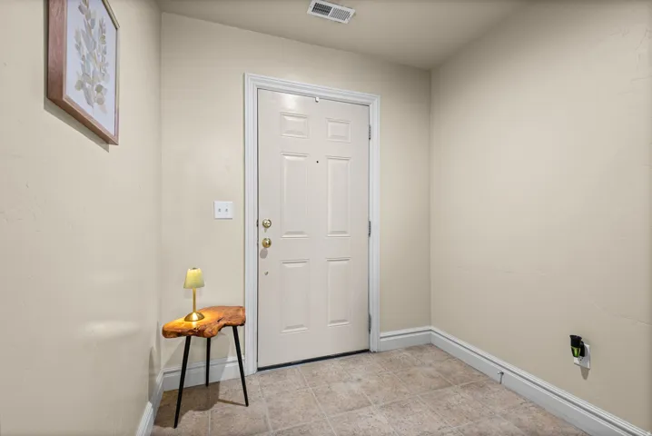 Entryway featuring a paneled door with brass hardware, light-toned wall paint, and tiled flooring